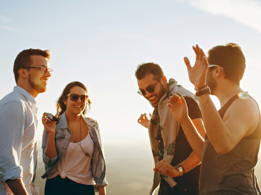 Four friends laughing together outdoors at sunset
